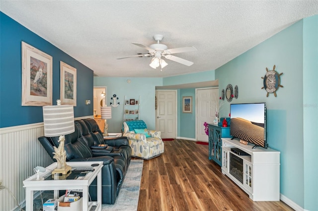 living room featuring ceiling fan, dark wood-type flooring, and a textured ceiling