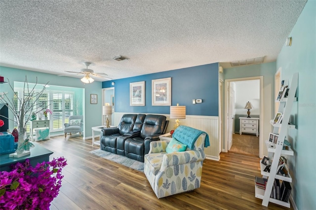 living room featuring dark hardwood / wood-style floors, ceiling fan, and a textured ceiling