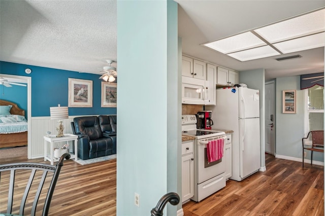 kitchen with white appliances, a skylight, dark hardwood / wood-style floors, ceiling fan, and white cabinetry