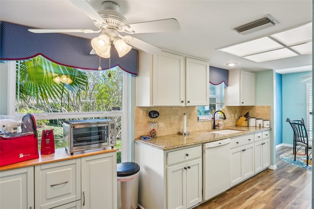 kitchen with white dishwasher, white cabinetry, tasteful backsplash, and sink