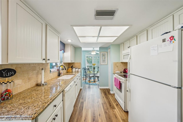 kitchen featuring light stone countertops, white appliances, sink, light hardwood / wood-style floors, and white cabinetry