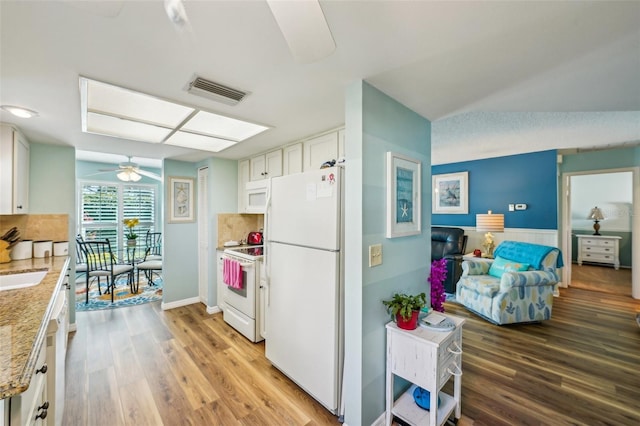 kitchen with white appliances, white cabinets, ceiling fan, light stone countertops, and light hardwood / wood-style floors