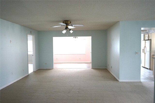 carpeted spare room featuring ceiling fan and a textured ceiling