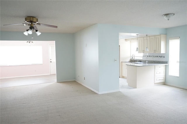 interior space featuring decorative backsplash, light colored carpet, ceiling fan, and sink