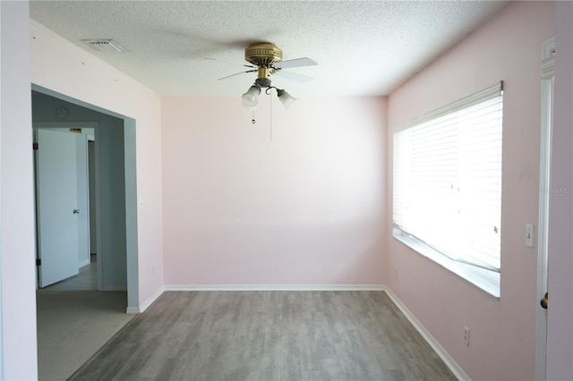 empty room with hardwood / wood-style flooring, ceiling fan, and a textured ceiling