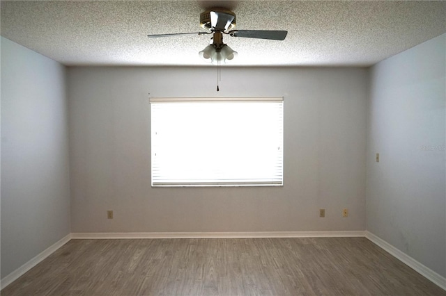 spare room with a textured ceiling, plenty of natural light, ceiling fan, and dark wood-type flooring