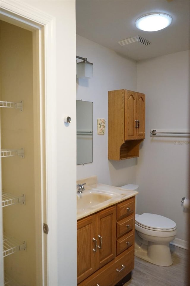 bathroom with wood-type flooring, vanity, and toilet