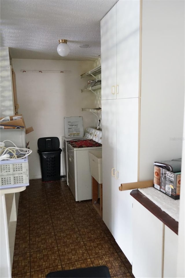 kitchen featuring washer and dryer, white cabinetry, and a textured ceiling