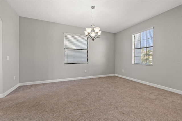 spare room with carpet floors and an inviting chandelier