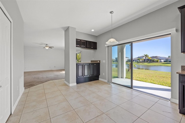 interior space with light tile patterned floors, a water view, and ceiling fan