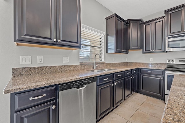 kitchen featuring appliances with stainless steel finishes, light stone counters, light tile patterned floors, and sink