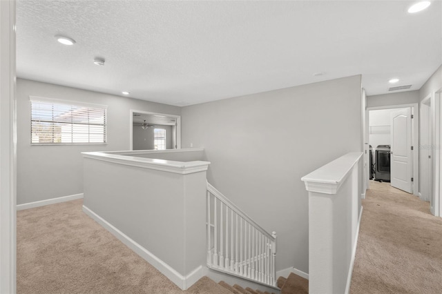 hall featuring a textured ceiling and light colored carpet