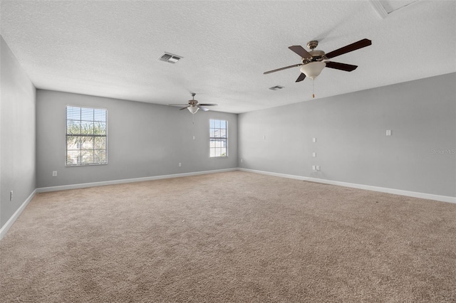 carpeted spare room with a wealth of natural light, ceiling fan, and a textured ceiling