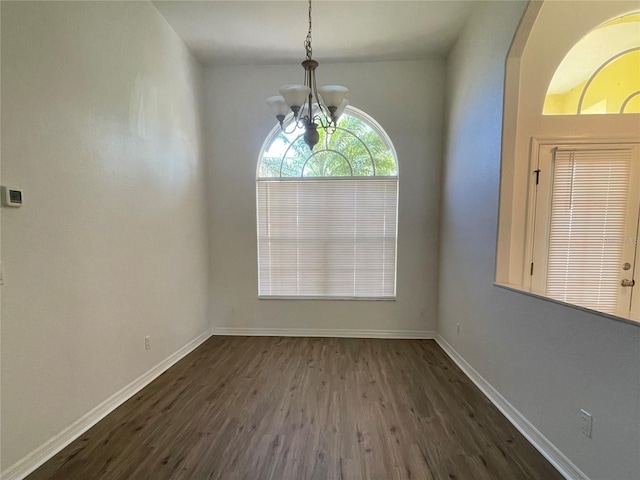 unfurnished dining area featuring dark hardwood / wood-style floors and an inviting chandelier