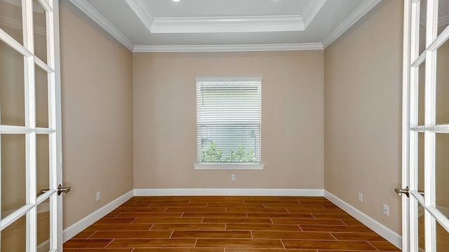 spare room with a raised ceiling, crown molding, and french doors