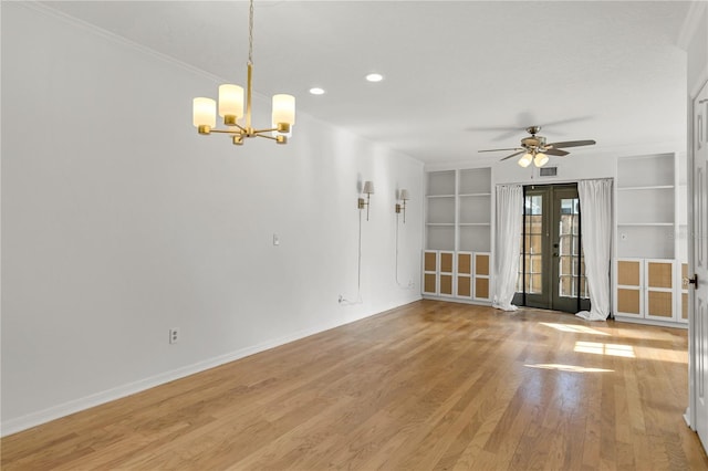 spare room with light hardwood / wood-style flooring, ceiling fan with notable chandelier, built in features, and french doors