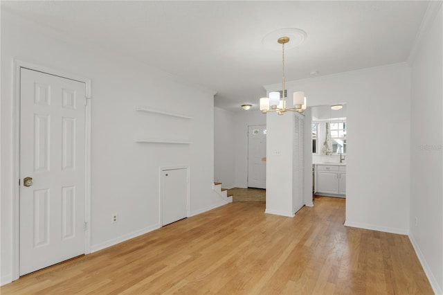 unfurnished dining area featuring sink, crown molding, light hardwood / wood-style flooring, and a chandelier