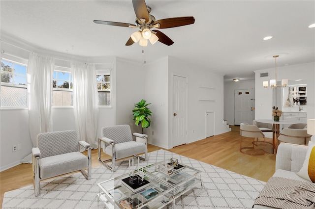 living room featuring ceiling fan with notable chandelier and light hardwood / wood-style flooring