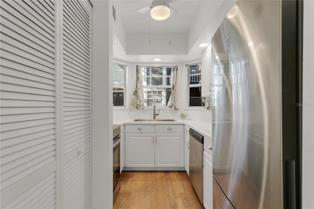 kitchen with white cabinetry, sink, light hardwood / wood-style flooring, and appliances with stainless steel finishes