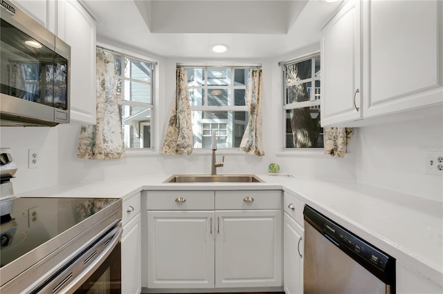 kitchen featuring white cabinetry, appliances with stainless steel finishes, a raised ceiling, and sink