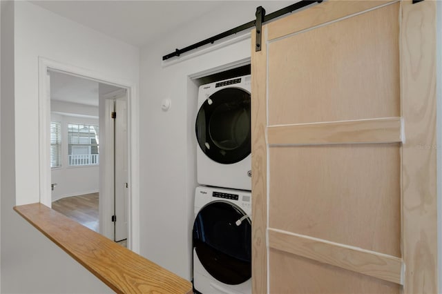 laundry area with a barn door and stacked washer and clothes dryer