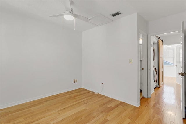 unfurnished room with stacked washer and clothes dryer, ceiling fan, and light wood-type flooring