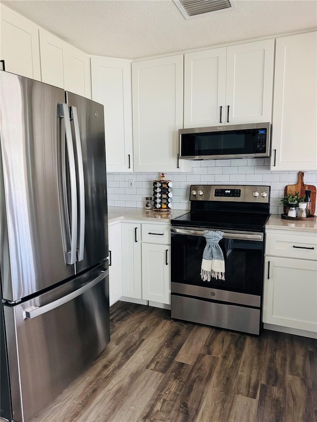 kitchen featuring decorative backsplash, stainless steel appliances, white cabinetry, and dark wood-type flooring