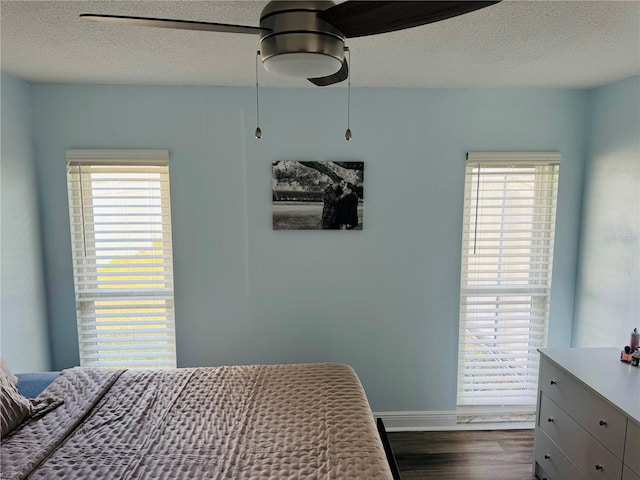 bedroom with ceiling fan, dark hardwood / wood-style floors, and a textured ceiling