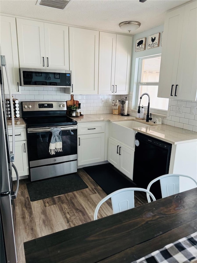 kitchen featuring sink, dark wood-type flooring, stainless steel appliances, decorative backsplash, and white cabinets