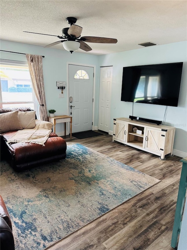 living room featuring ceiling fan, dark hardwood / wood-style flooring, and a textured ceiling