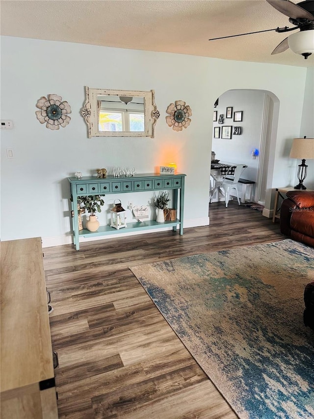 unfurnished living room featuring a textured ceiling, dark hardwood / wood-style floors, and ceiling fan