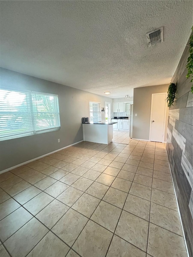 unfurnished living room with a textured ceiling and light tile patterned floors