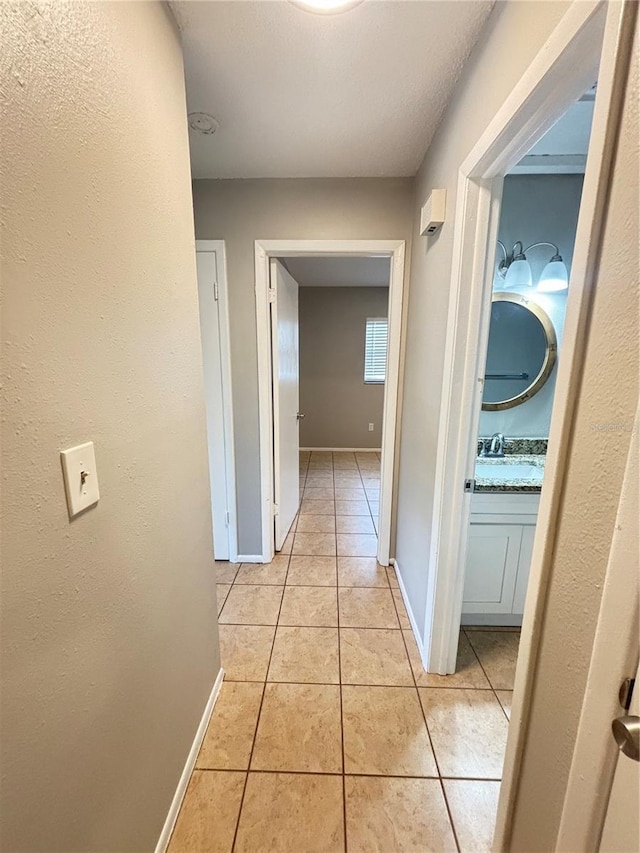 hallway with light tile patterned flooring and sink