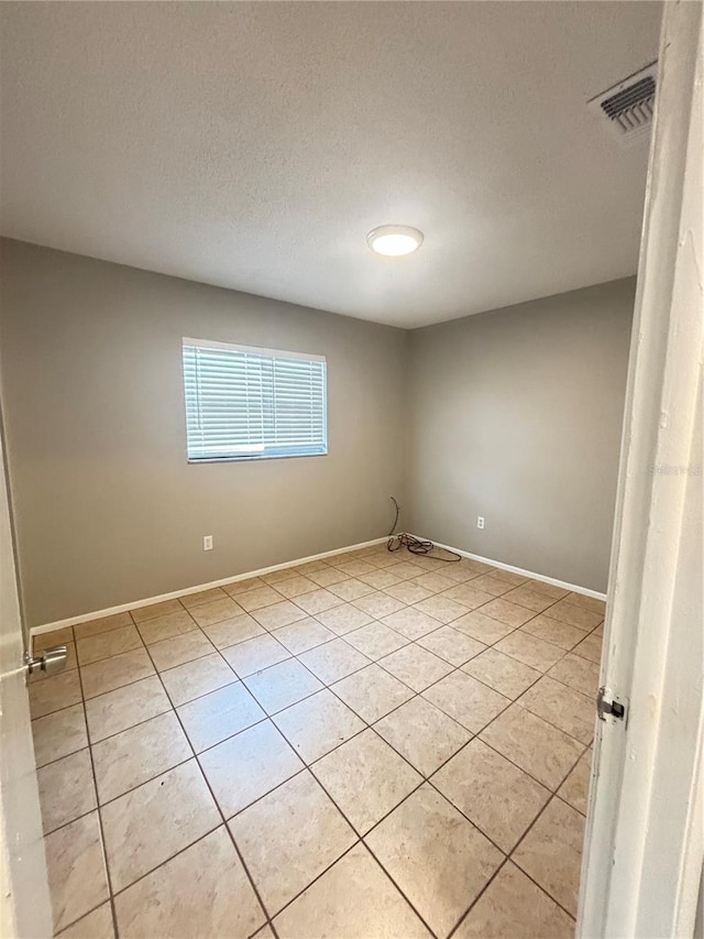 spare room with a textured ceiling and light tile patterned floors