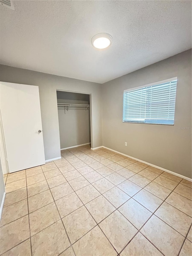 unfurnished bedroom featuring light tile patterned floors, a closet, and a textured ceiling