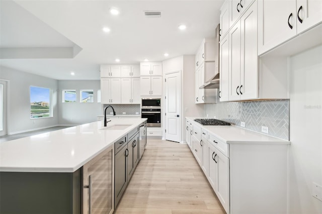 kitchen with wine cooler, white cabinetry, and sink