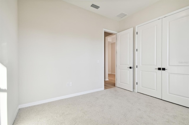 unfurnished bedroom with light carpet and a closet