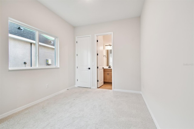 unfurnished bedroom featuring light carpet and ensuite bath