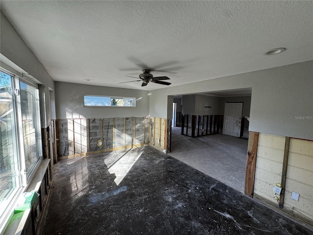 unfurnished living room featuring ceiling fan and a textured ceiling