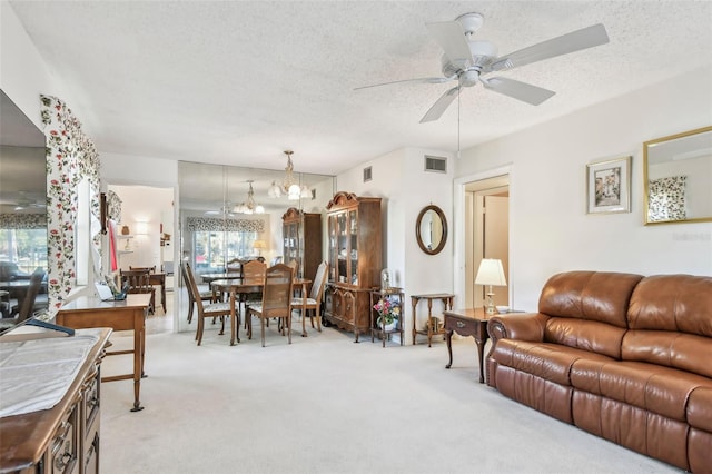 carpeted living room with ceiling fan with notable chandelier and a textured ceiling