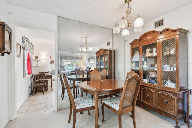 tiled dining space featuring a textured ceiling and an inviting chandelier