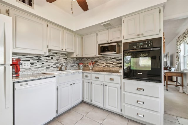 kitchen with backsplash, white appliances, sink, light tile patterned floors, and white cabinets