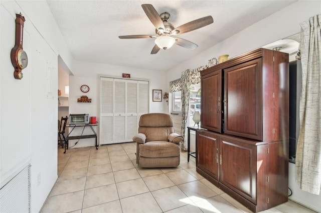 living area with ceiling fan, light tile patterned floors, and a textured ceiling