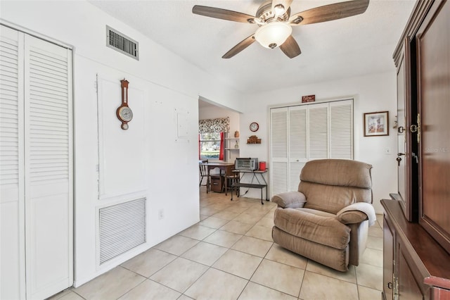 sitting room with ceiling fan, light tile patterned flooring, and a textured ceiling