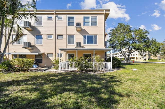 rear view of property featuring a porch, a yard, and central AC