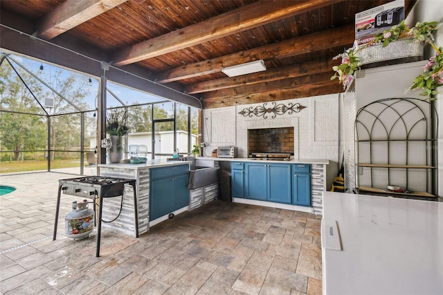 view of patio with a lanai, an outdoor kitchen, a fireplace, and exterior bar