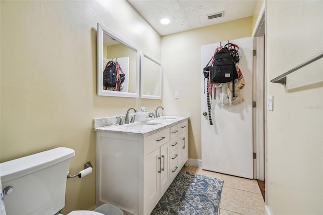 bathroom featuring toilet, vanity, tile patterned flooring, and a textured ceiling