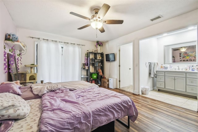 bedroom with ceiling fan, connected bathroom, light hardwood / wood-style flooring, and sink