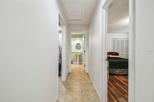 hall with a textured ceiling and light tile patterned flooring