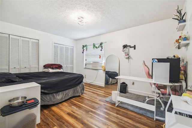 bedroom featuring wood-type flooring, a textured ceiling, and two closets